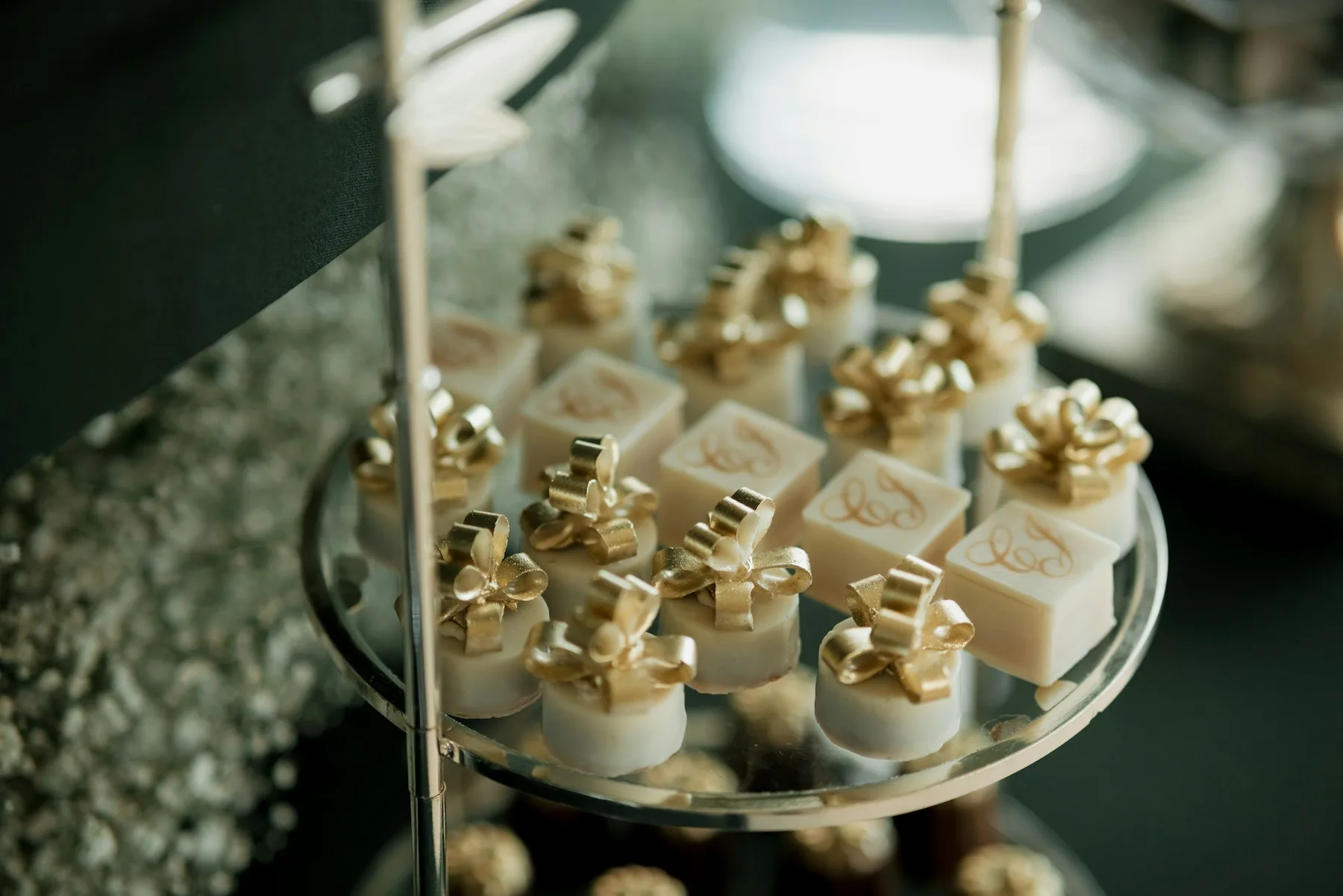 Petits gâteaux individuels à nœuds de sucre dorés sur un présentoir miroir